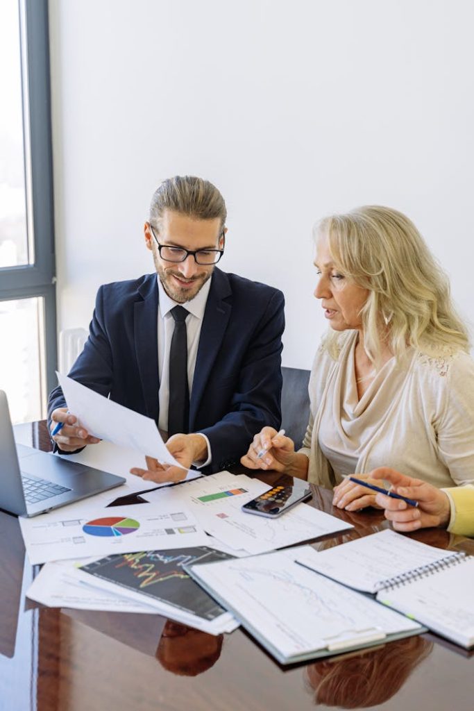 a-man-and-a-woman-discussing-a-document-5816300 Two business professionals reviewing financial documents and graphs during a meeting.