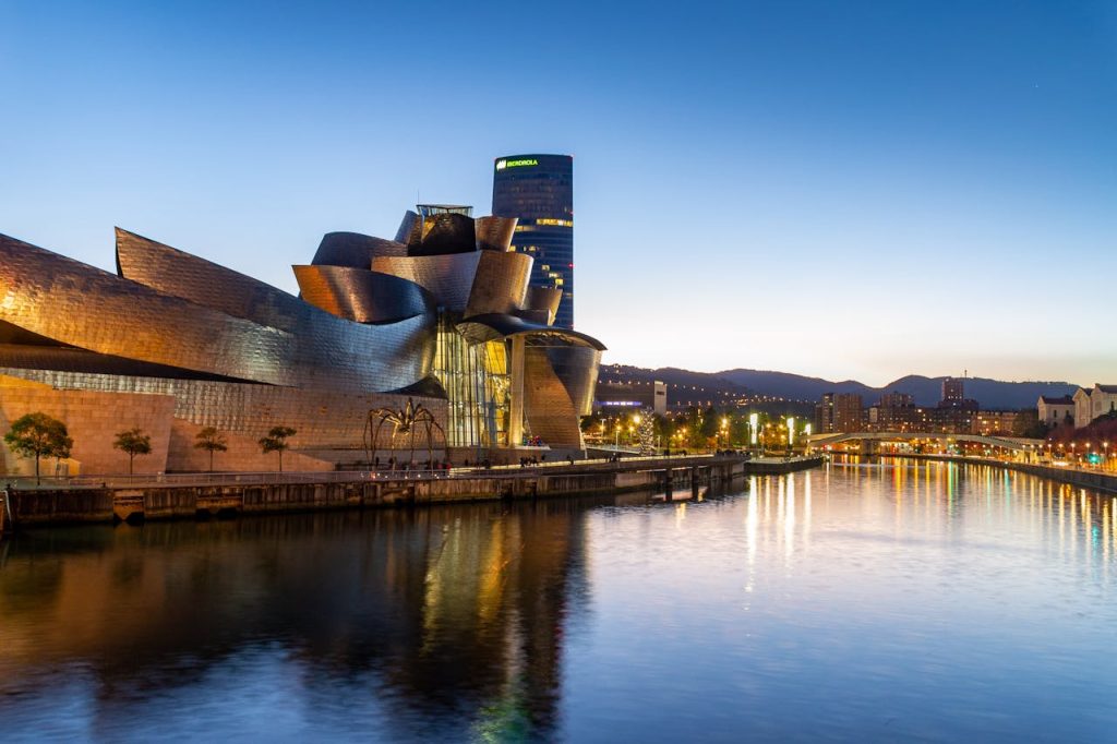 guggenheim-museum-bilbao-in-spain-10473354 Stunning view of the Guggenheim Museum Bilbao reflecting in the Nervion River at dusk.