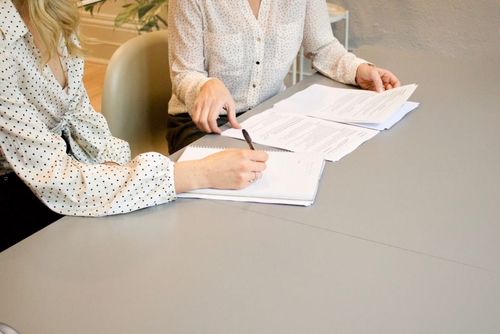 woman-signing-on-white-printer-paper-beside-woman-about-to-touch-the-documents-hjckknwcxxq woman-signing-on-white-printer-paper-beside-woman-about-to-touch-the-documents-hjckknwcxxq
